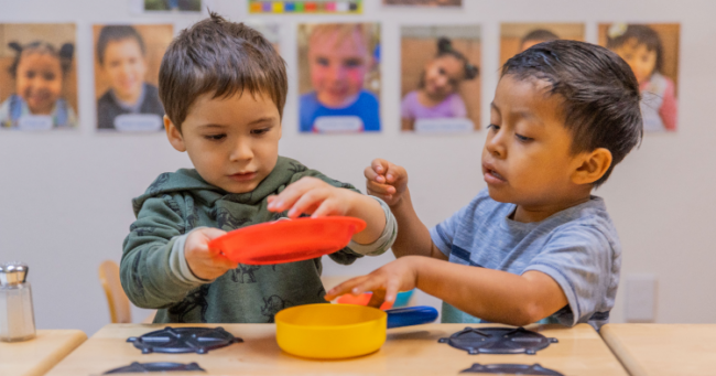 Toddler boy in green shirt shred with toddler boy in blue shirt