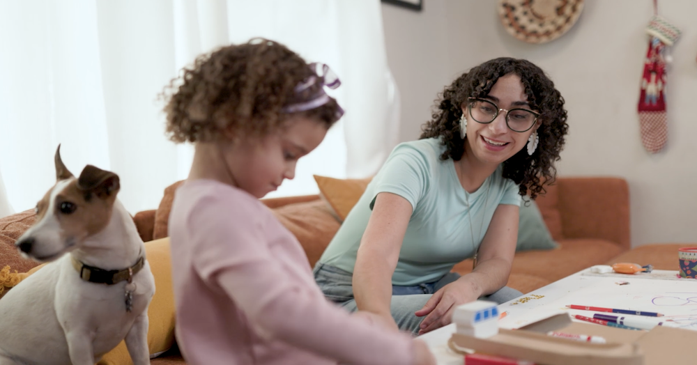 dog, toddler girl and mother coloring in living room