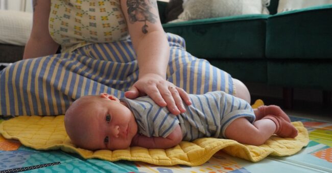 newborn baby doing tummy time next to mom
